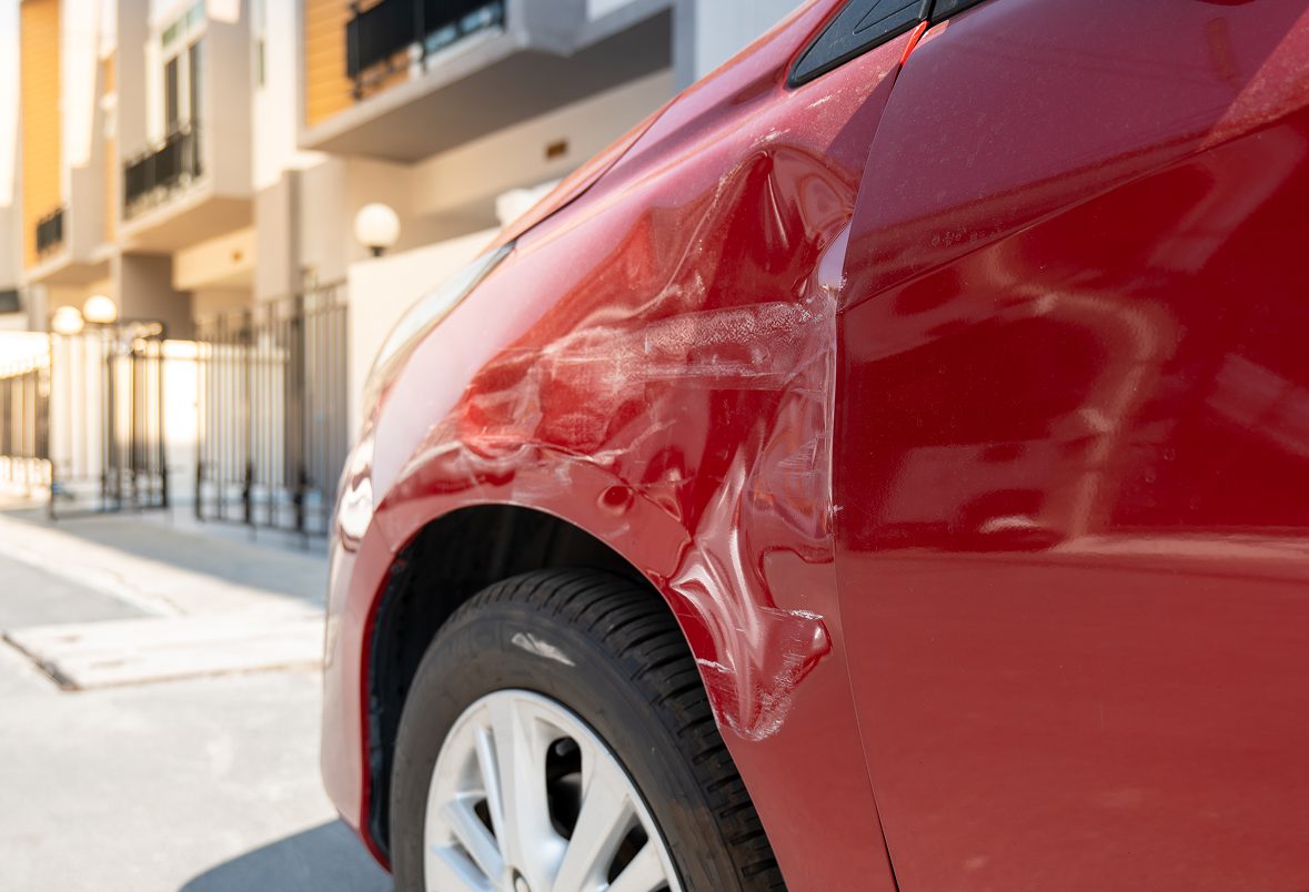 Red car with dented rear fender.