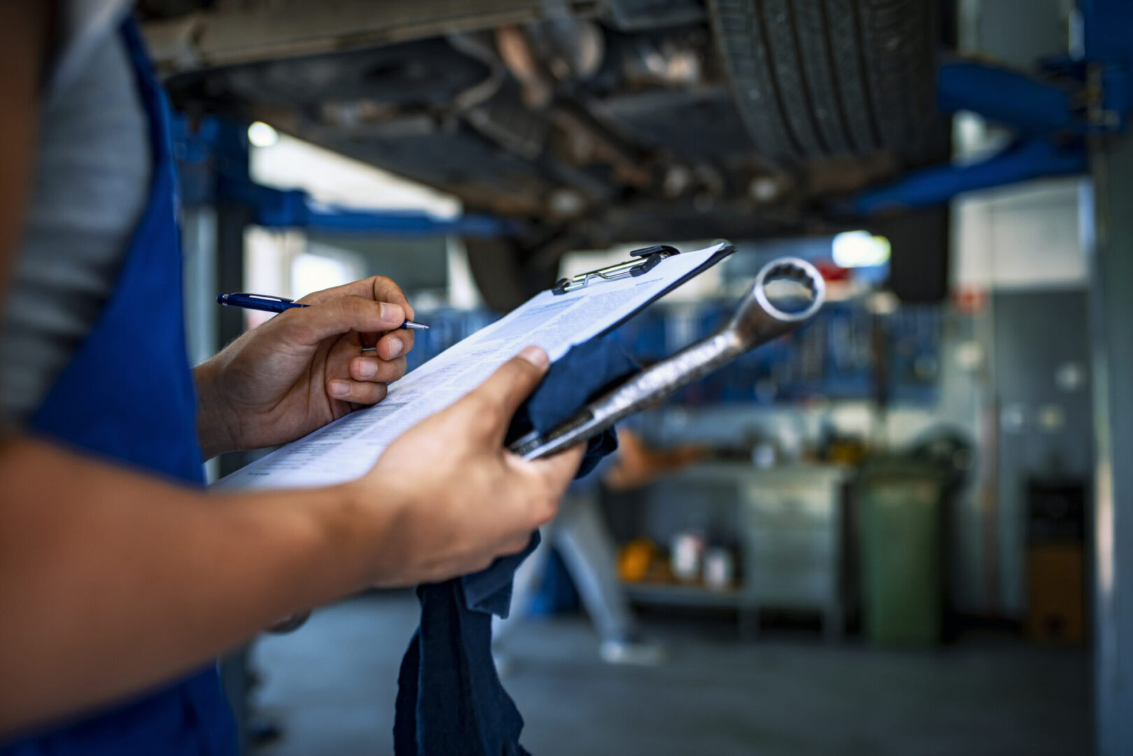 Mechanic inspecting vehicle with checklist and tools.
