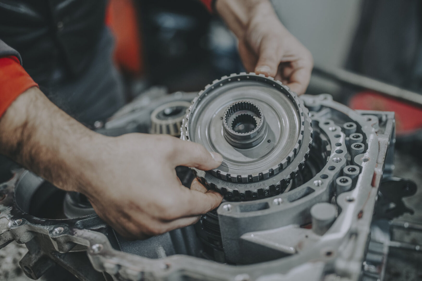 Mechanic working on car transmission gear.