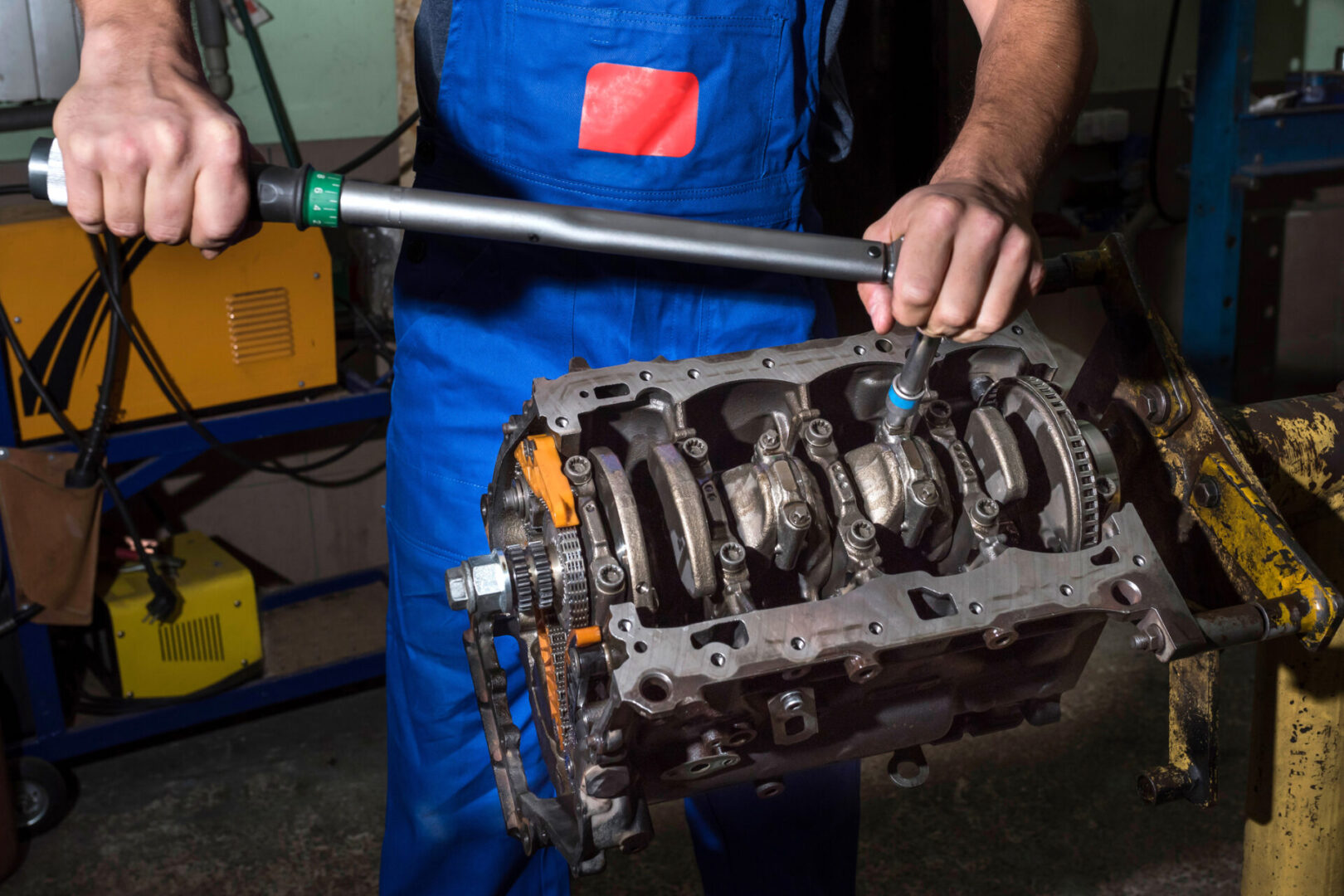 Mechanic working on engine block disassembly.