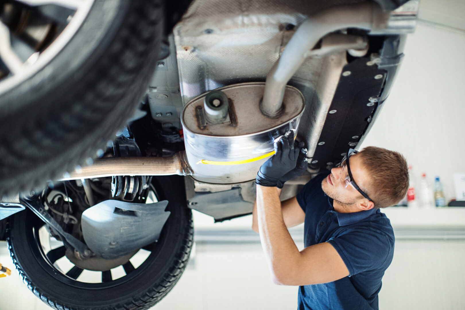 Mechanic inspecting undercarriage of a vehicle.