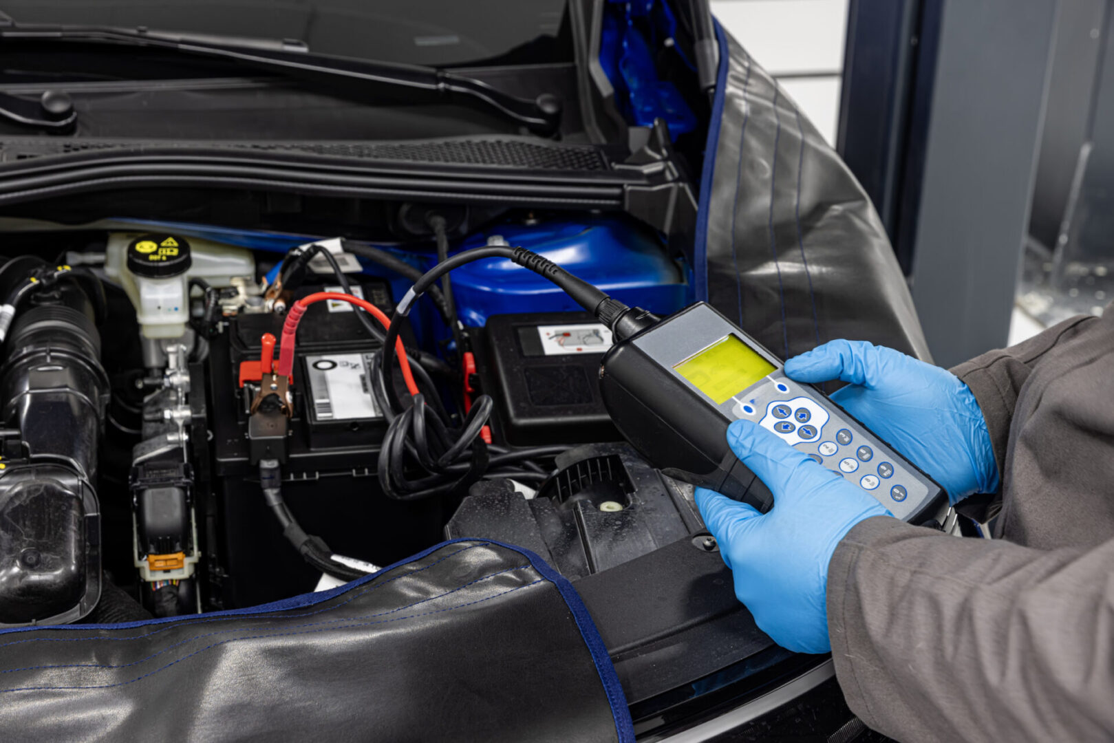Mechanic testing car battery with diagnostic tool.