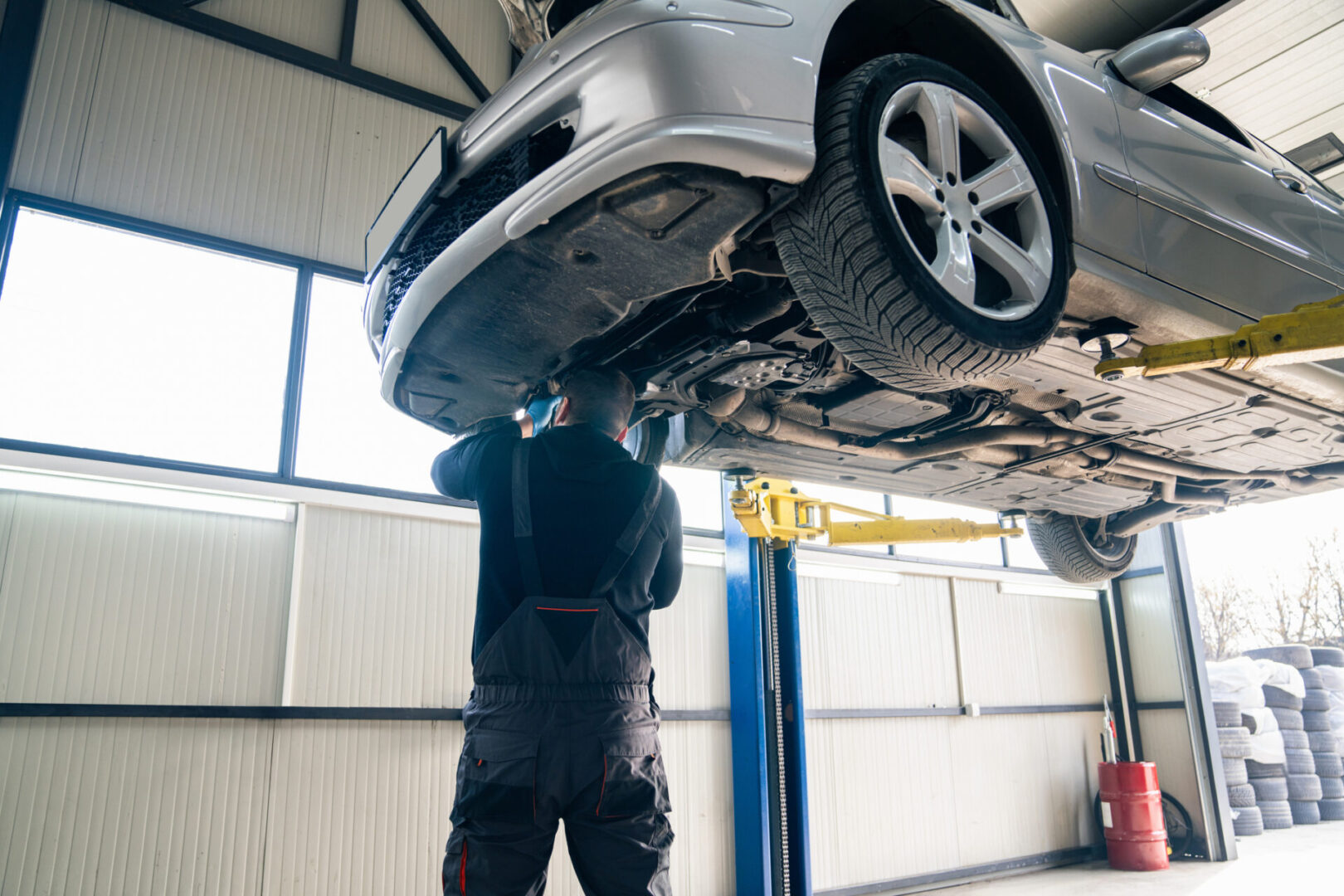 Mechanic inspecting car on hydraulic lift.