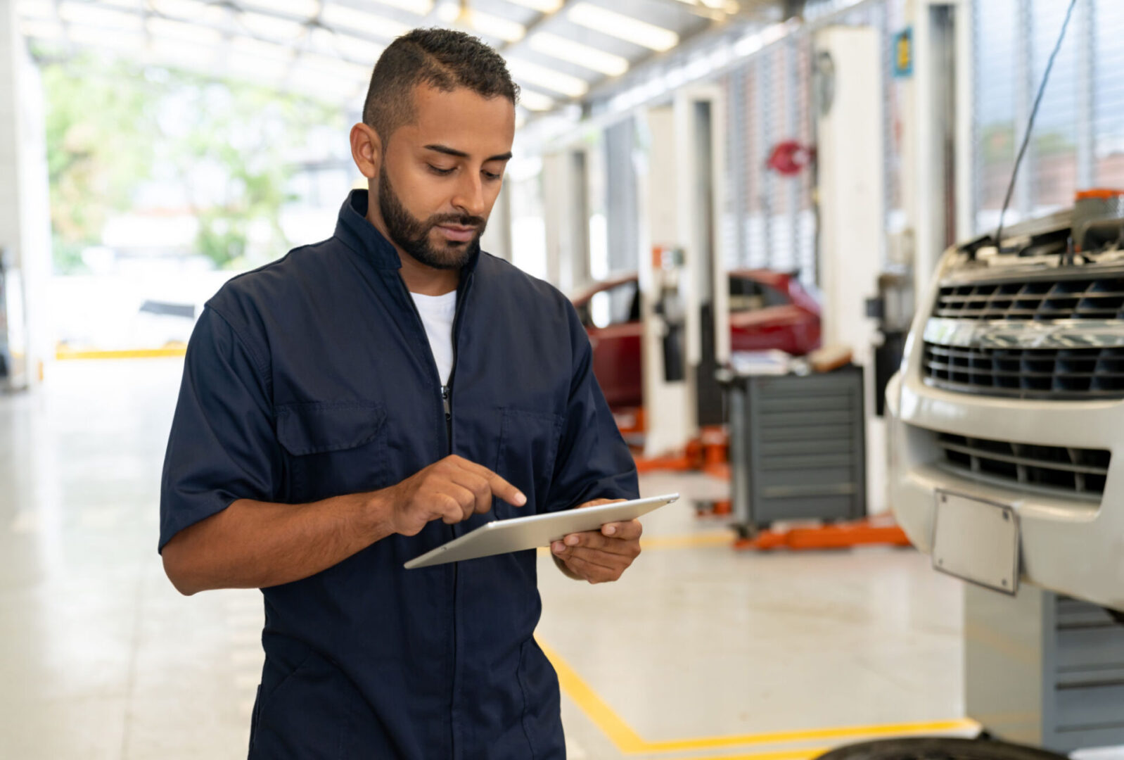 Mechanic using tablet in auto repair shop.