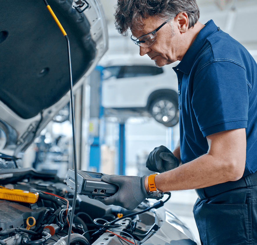 Mechanic using diagnostic tool on car engine.